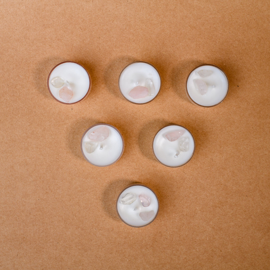 Six gemstone tealight candles with white wax on a brown surface, crystal decor