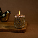 Load image into Gallery viewer, Decorative floral glass candle burning on wooden tray with gold bird figurine