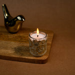 Load image into Gallery viewer, Decorative glass candle burning on wooden tray with gold bird figurine, brown background