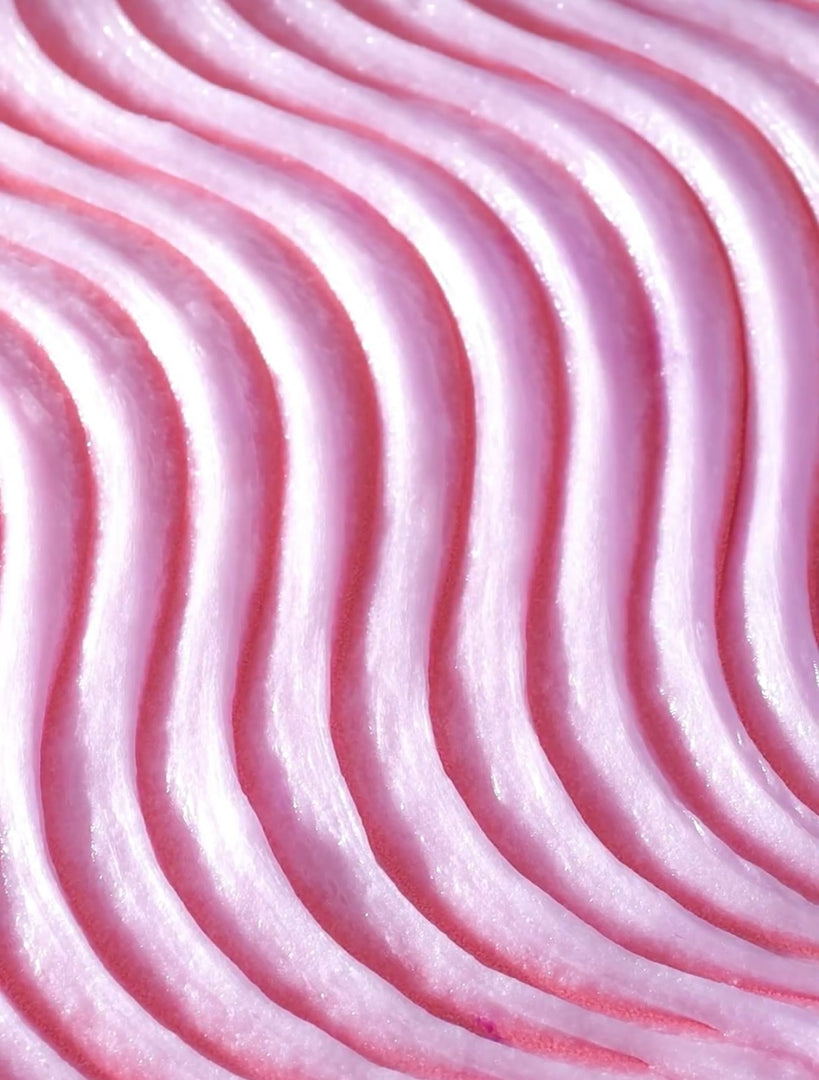 Close-up of textured pink buttercream frosting with wavy, even piping lines