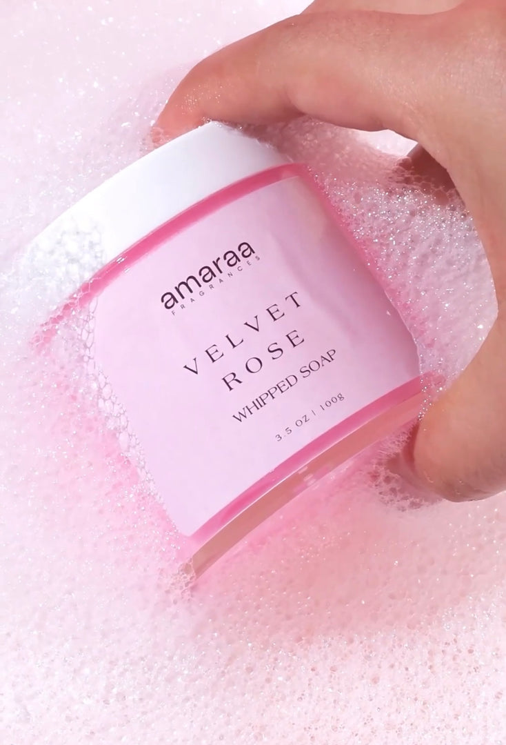 Hand holding Amaraa Velvet Rose Whipped Soap jar in pink bubbly foam