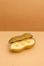 Load image into Gallery viewer, Gold peanut-shaped candle holder with three lit candles on a beige background