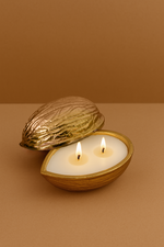 Load image into Gallery viewer, Gold walnut shell candle with two wicks on a beige background